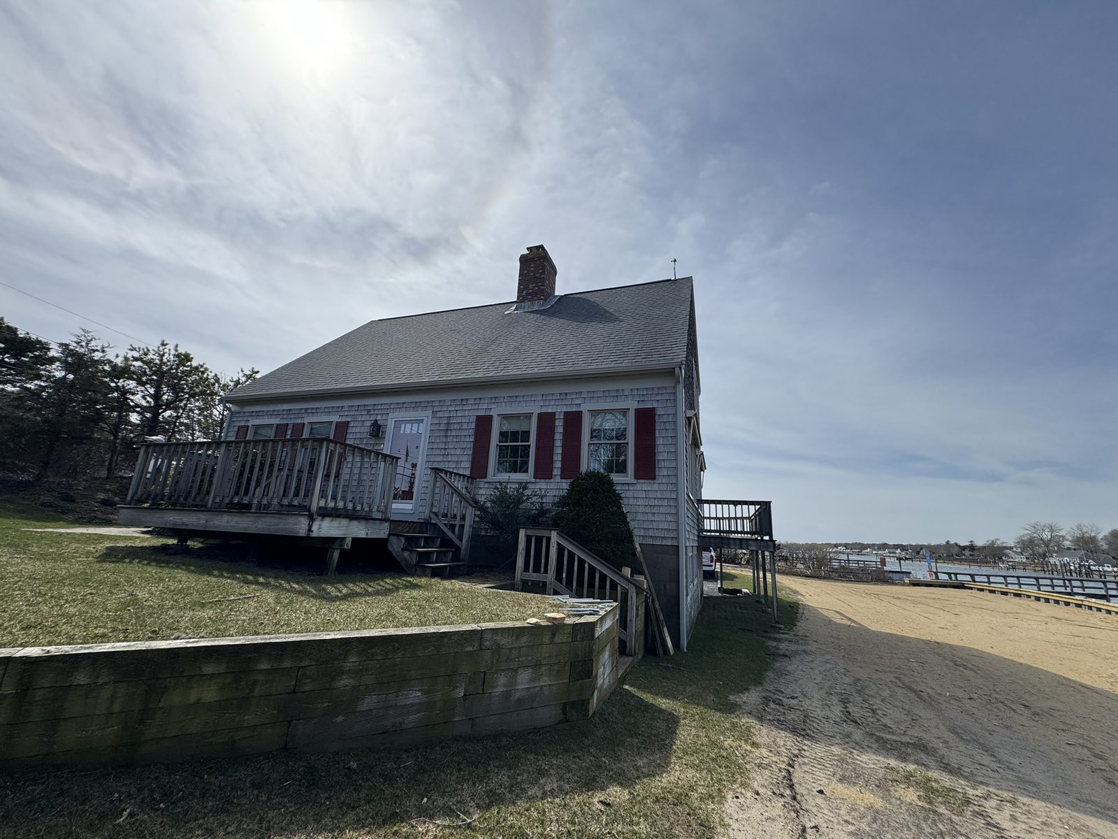 Cedar shingle Cape Cod home with red shutters near waterfront