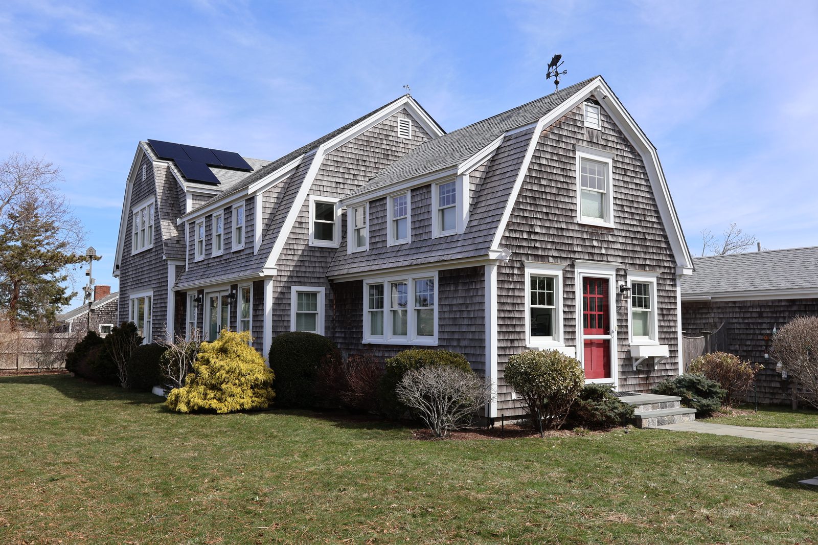 Cape Cod gambrel shingle home with red door and weather vane