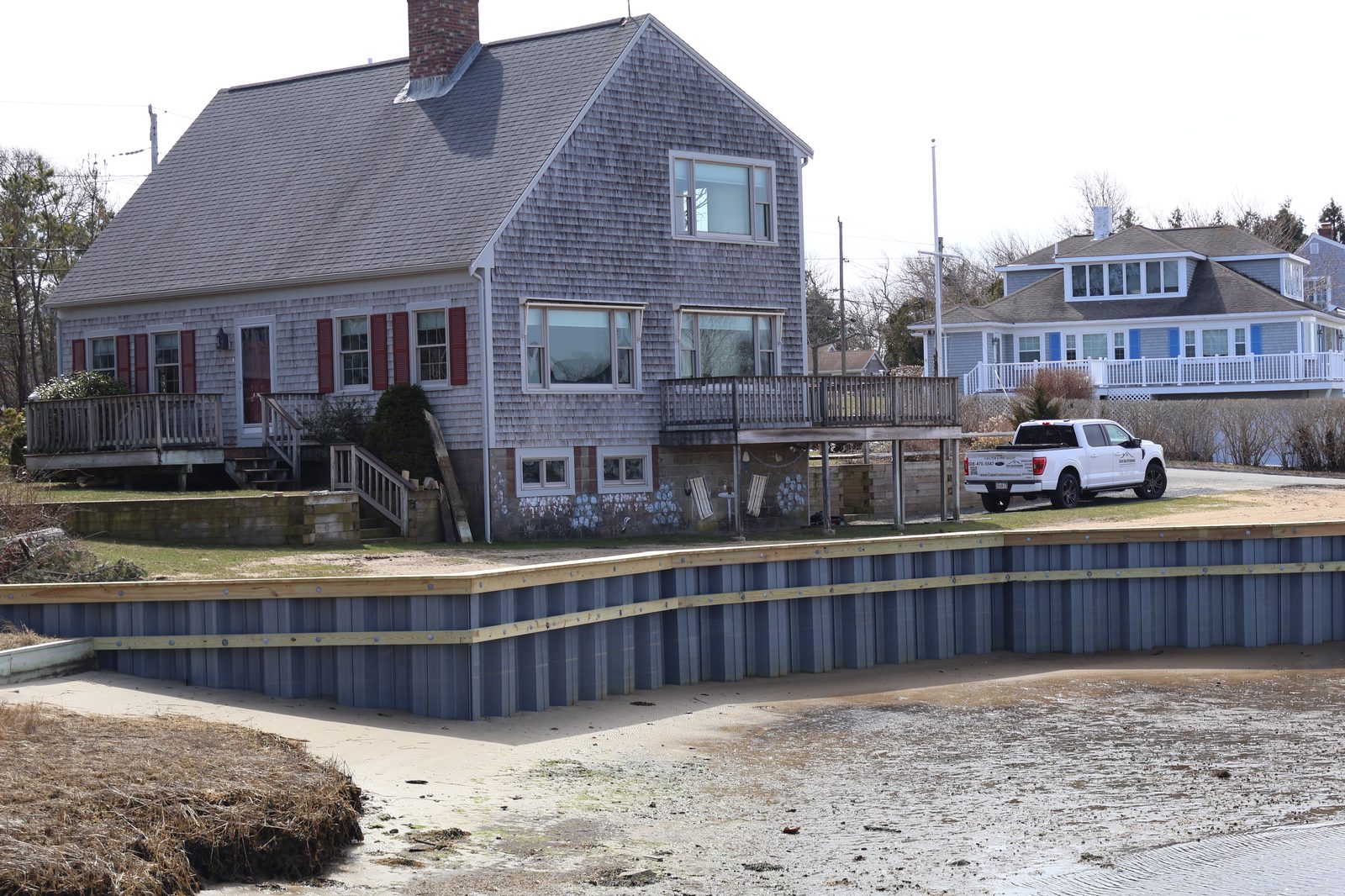 Waterfront Cape Cod home with cedar shingles and red shutters